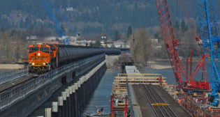 Unit crude from North Dakota to the Pacific Northwest crosses Lake Pend Oreille outside Sandpoint, Idaho, on April 29, 2023, using BNSF’s new bridge that entered service in November 2022. Workers on the older, adjacent bridge are placing concrete caps on new piers as part of a major renovation of the 119-year-old structure. (Photograph and Caption, Bruce E. Kelly)
